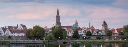 Sonnenuntergang mit lilalem Himmel. Man sieht die Ulmer Stadtsilouhette. Der Münsterturm sticht hervor.