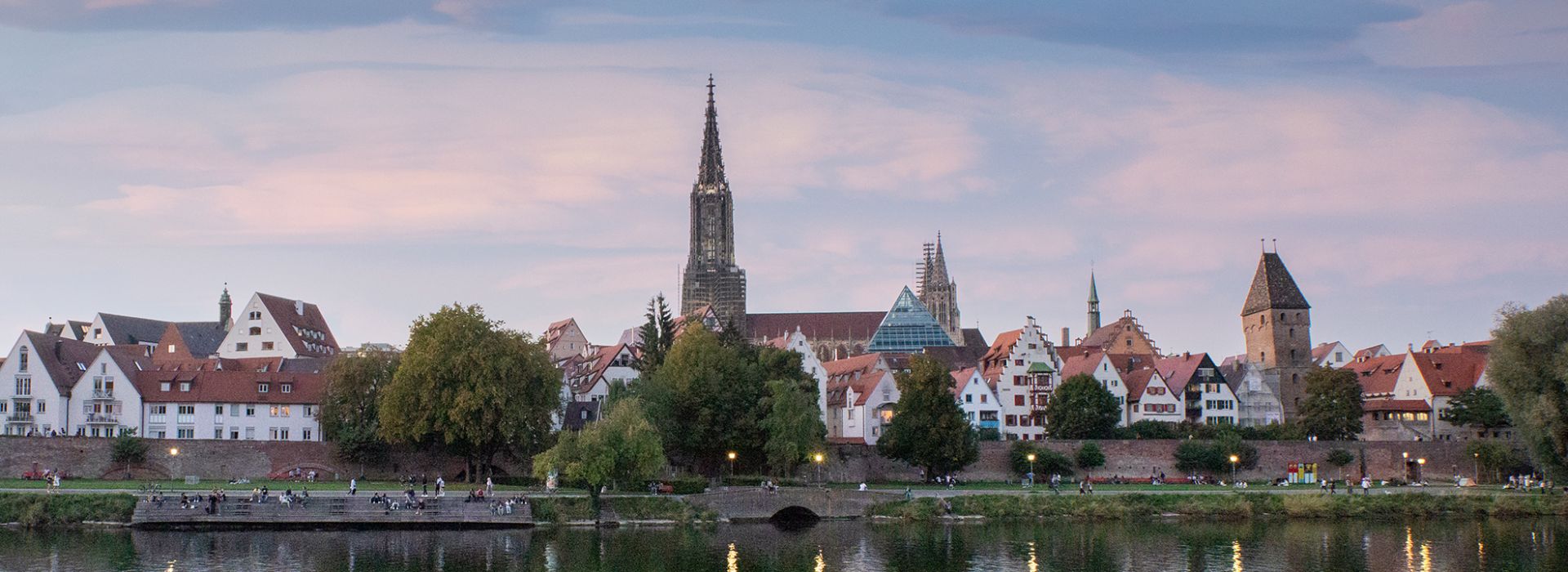 Sonnenuntergang mit lilalem Himmel. Man sieht die Ulmer Stadtsilouhette. Der Münsterturm sticht hervor.