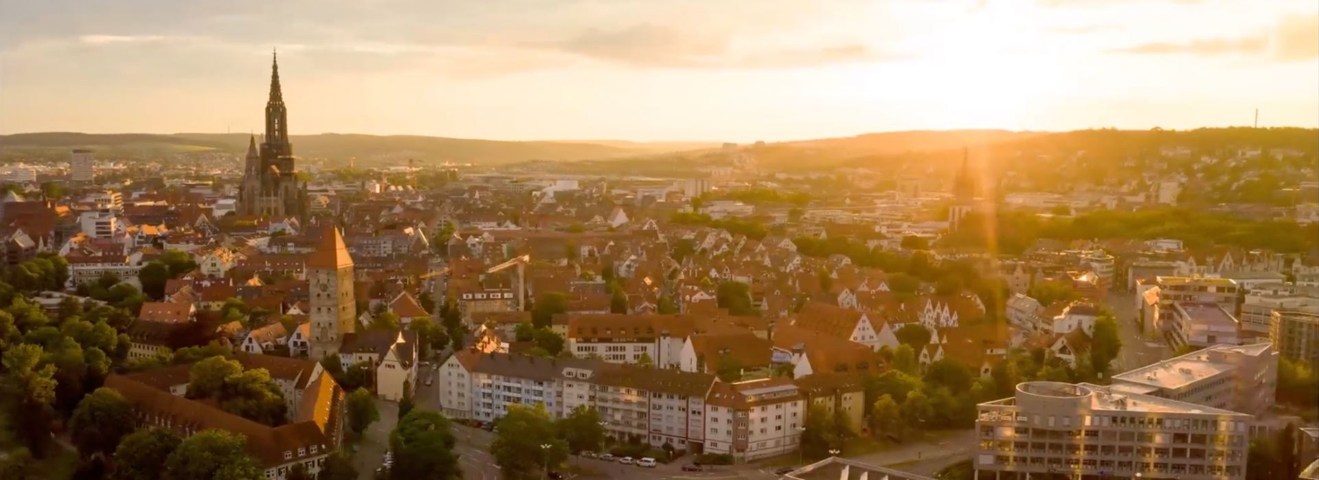 Stadtpanorama von Ulm bei Sonnenuntergang mit dem Ulmer Münster als zentrales Wahrzeichen.