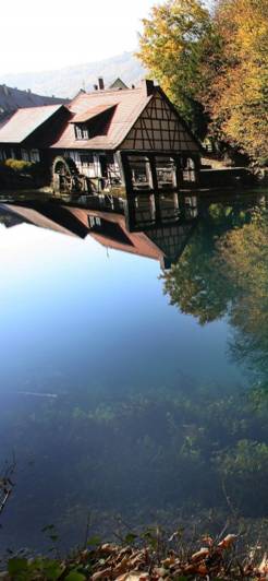 Der Blautopf in Blaubeuren mit seinem klaren, blauen Wasser und einem malerischen Fachwerkhaus mit Mühlrad am Ufer