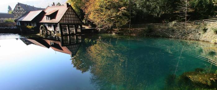 Der Blautopf in Blaubeuren mit seinem klaren, blauen Wasser und einem malerischen Fachwerkhaus mit Mühlrad am Ufer