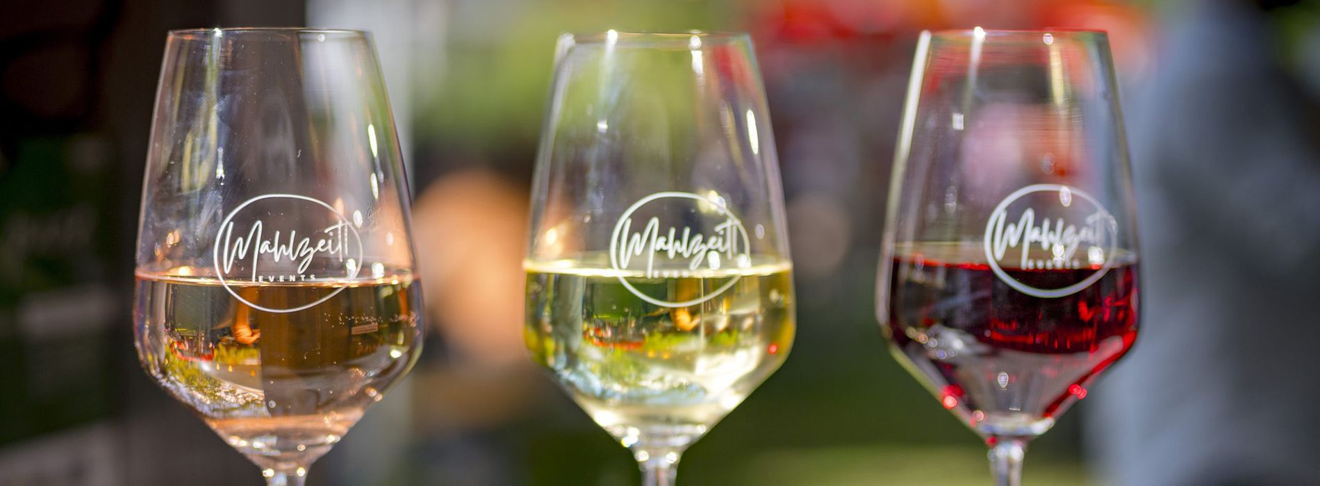 Drei Weingläser stehen nebeneinander. Eins mit Weisswein, eins mit Rosé und eins mit Rotwein gefüllt.